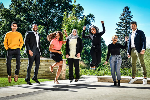A diverse group of students jump together on Fisher campus.