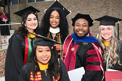 Students celebrate with faculty at graduation.