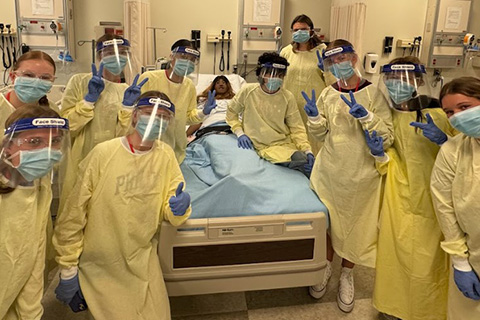 Students in personal protective equipment give two thumbs up during Cardinal Nurse Camp.