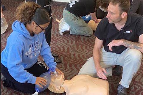 A student practices CPR on a mannequin.