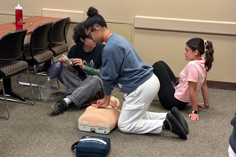 A student practices CPR on a mannequin.