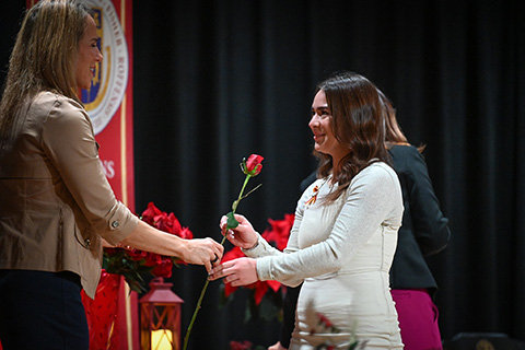 Dr. Christine Boev presents a rose to a graduating nursing student.