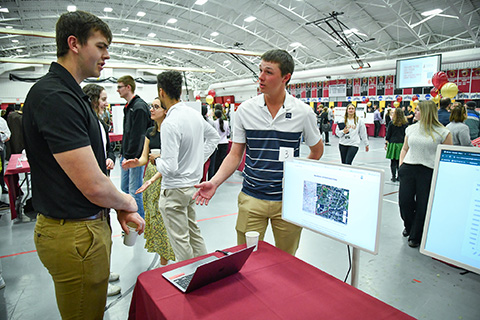 A student shares her research on a poster at the Fisher Showcase.