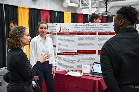 A student shares research on a laptop at the Fisher Showcase.