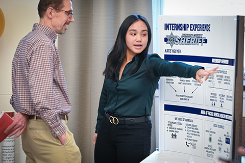 A student shares her research on a poster at the Fisher Showcase.