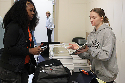 A student gives an overview of the iPad to a new student.