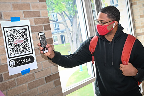 A student scans a QR code with his phone during iPad deployment.