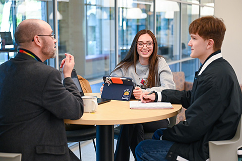 Students sit with a librarian to work on a project.