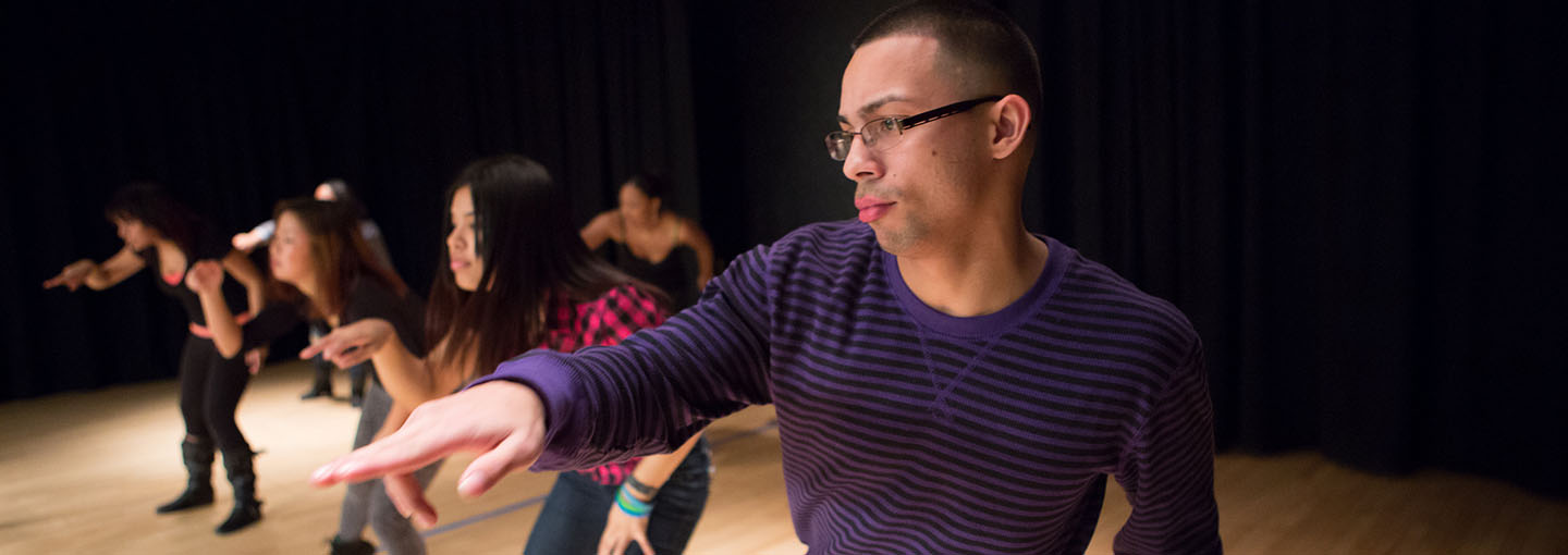 Students perform a dance on stage as part of the Arts in Motion group