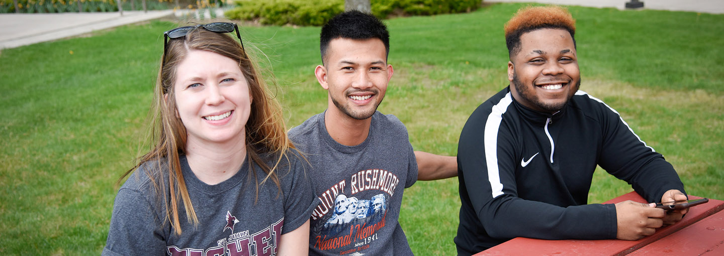 Three Fisher students at a picnic table.