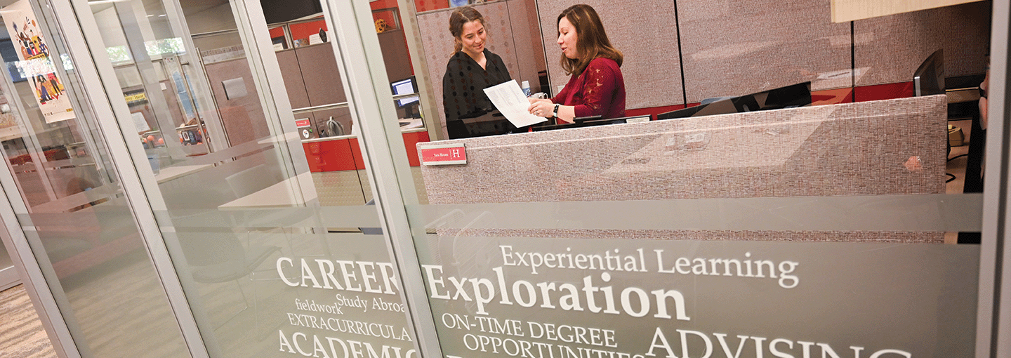 A Fisher student meets with a career planning advisor near a sign for career exploration.