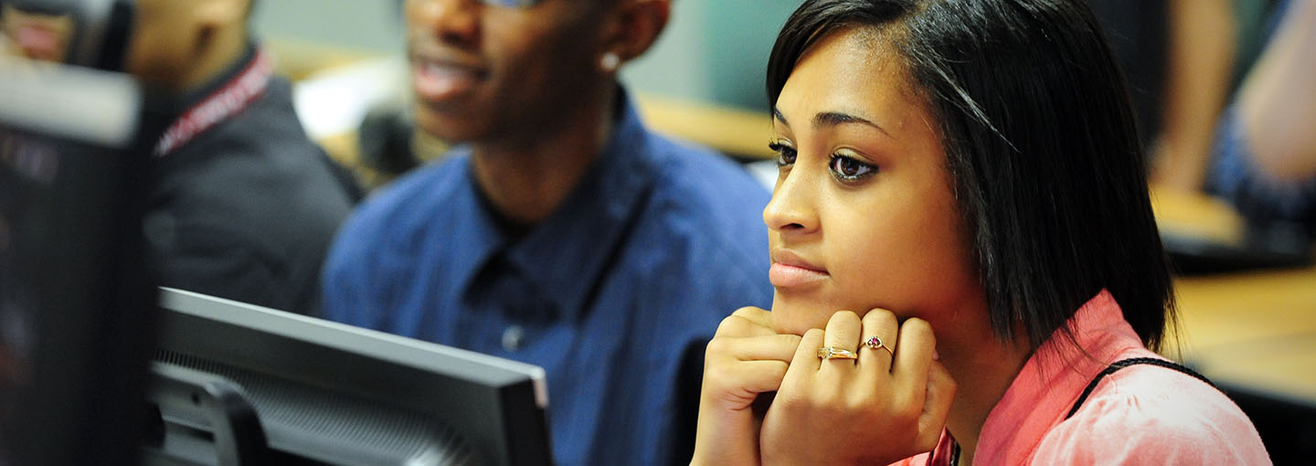 College Bound participant with chin in hands in a computer lab.