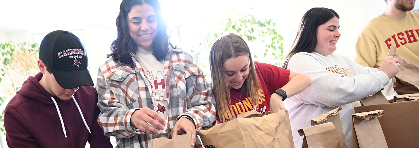 A group of students packing lunch bags in a brightly lit space.