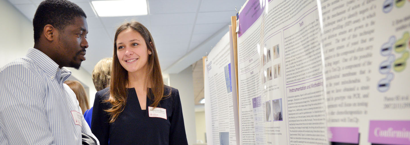 Two students in front of a science poster.