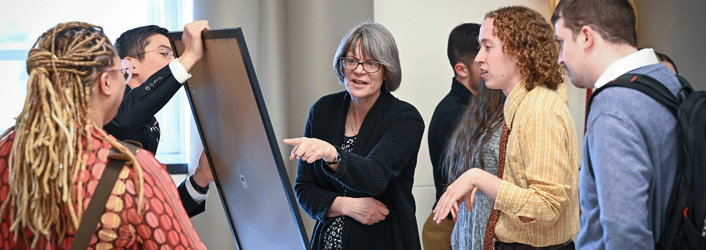 Students and professors discuss student research on display at the Fisher Showcase.