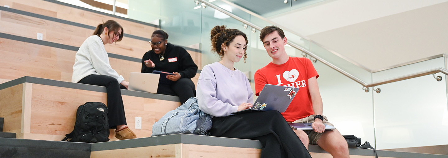 Male and female students on the social stairs in the library studying.