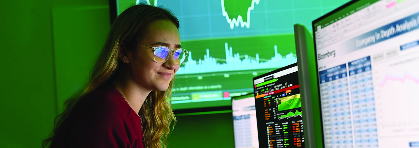 A female student looking at a Bloomberg computer terminal in Fisher's trading lab.