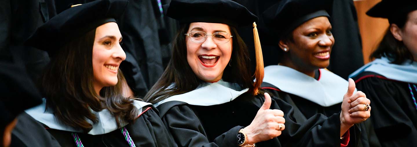 Ed.D. graduates celebrate with two thumbs up.