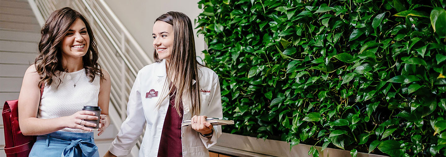 Pharmacy students walk near a green wall