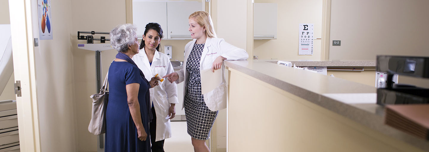 Professor with pharmacy students consulting with client.