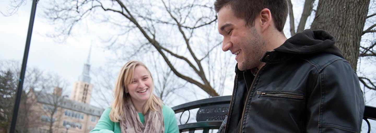 Two students smiling on bench outside