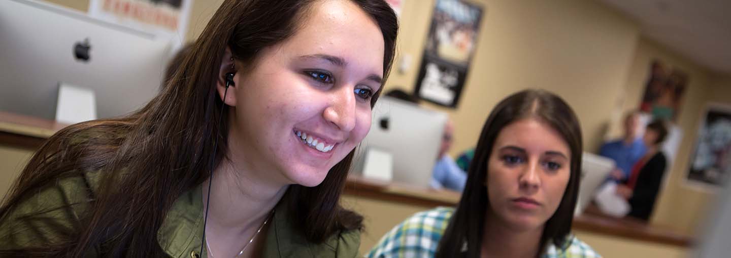 Two students in front of Mac computers