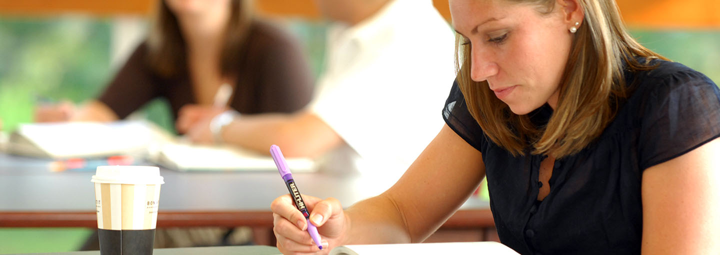 Student studying textbook with highlighter in hand