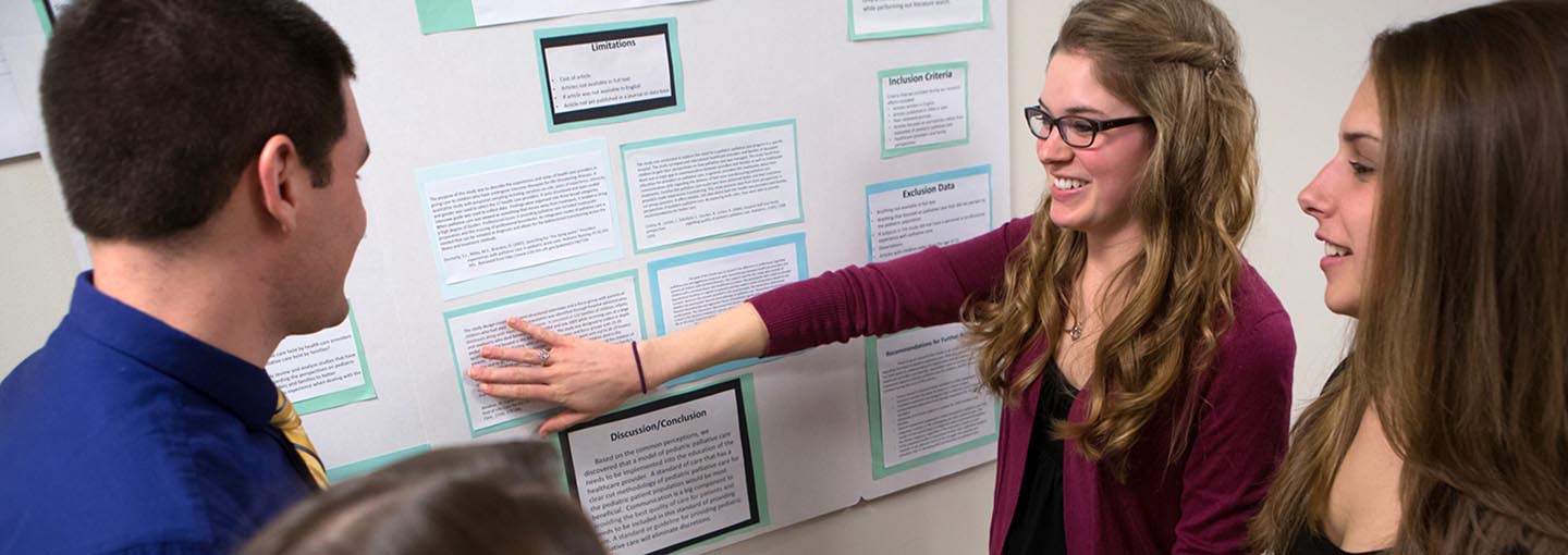 Several students gathered around an academic poster