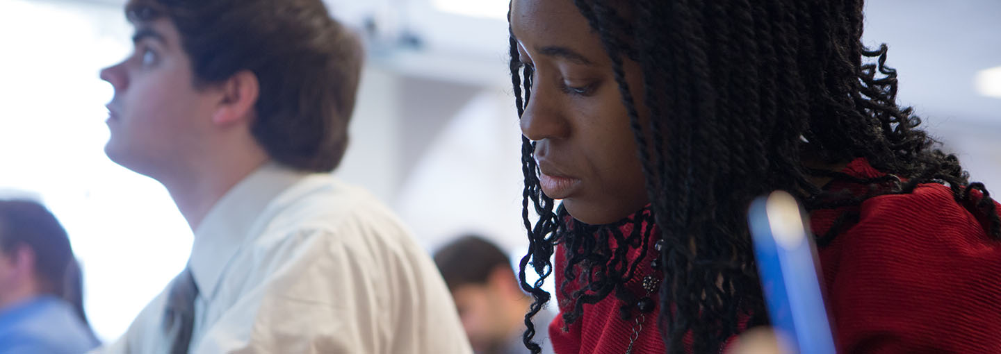 A student is focused on writing in a classroom.