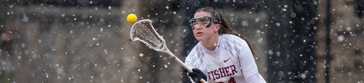 A member of the Fisher womens lacrosse team catches the ball in the snow.