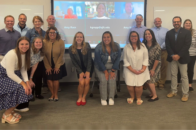 A group gathered together in front of a screen