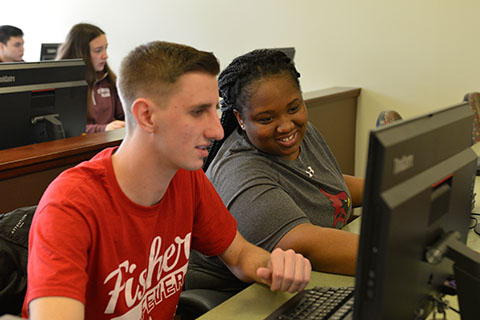 Two students look at computer screen  together.