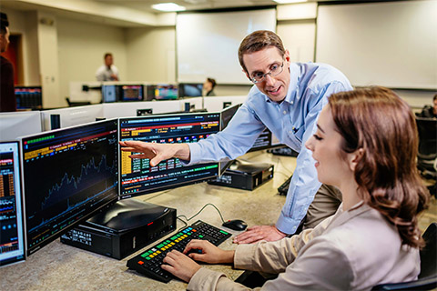 A faculty member helps a student at a computer.