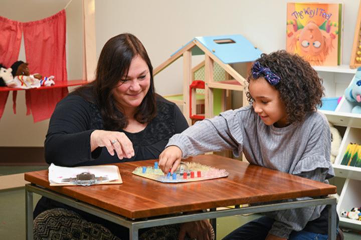 An adult and a child play a game together in the pediatric mental health counseling space at St. John Fisher University.