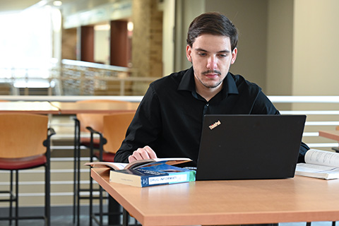 A graduate student works on a laptop.