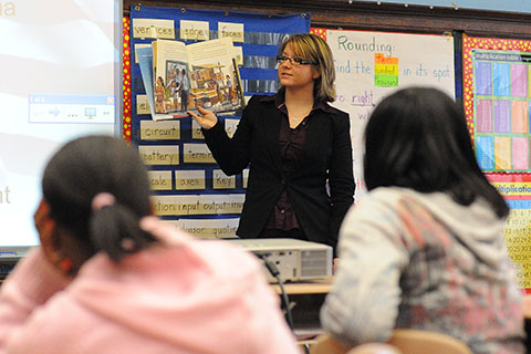 Teacher reading in front of class of adolescents.