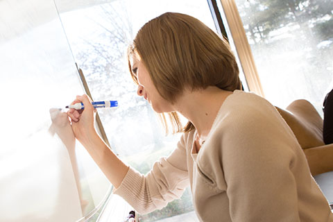 A woman writes on a whiteboard.