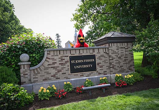 Cardinal mascot on brick sign of St. John Fisher University.