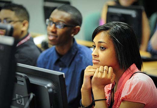 College Bound participant with chin in hands in a computer lab.