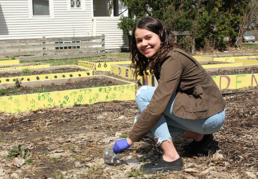 A student works in a community garden as part of a community-engaged learning course.