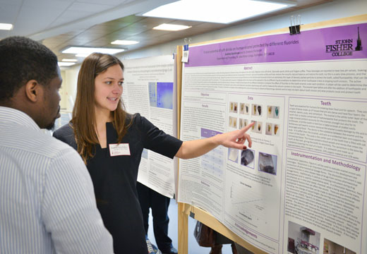 Student pointing to science research poster.