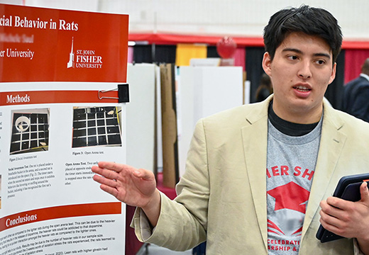 Student explains a poster at Fisher Showcase Research Symposium.