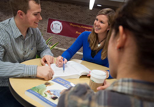 Students sitting around table in pharmacy atrium.