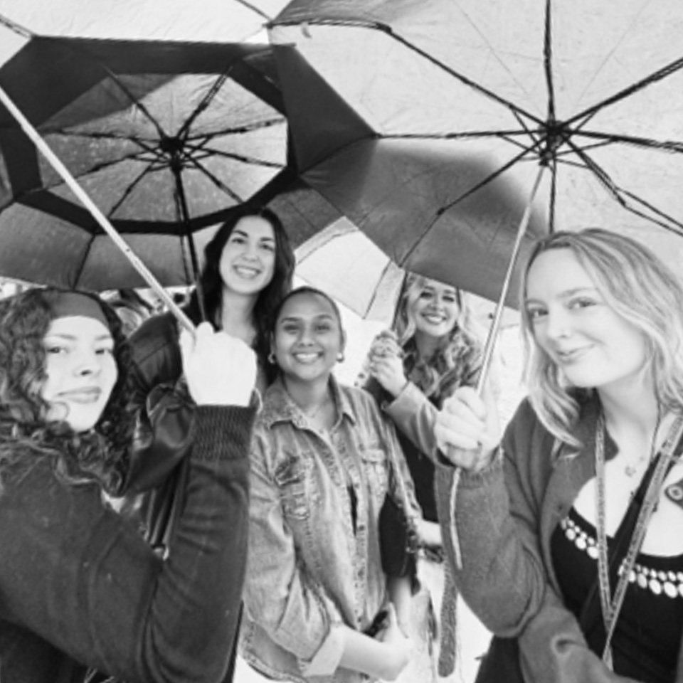 Students studying abroad stand with umbrellas in Italy.