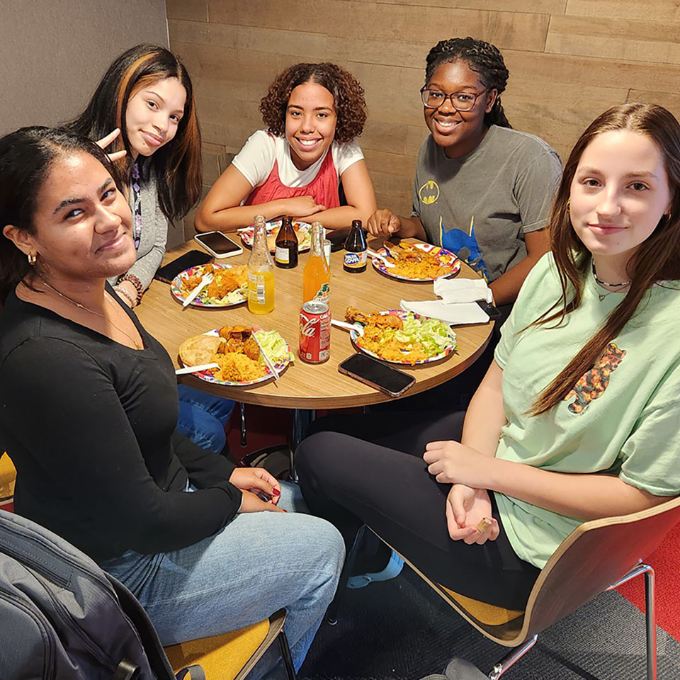 A group of students enjoy a meal together at a club on campus.