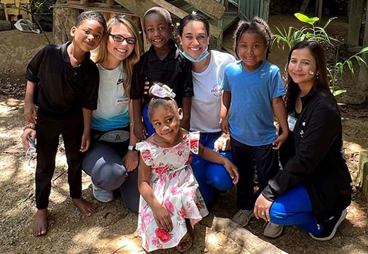 Sara Riforgiat, second from the left, kneels beside children from the community where she served and two nursing students.