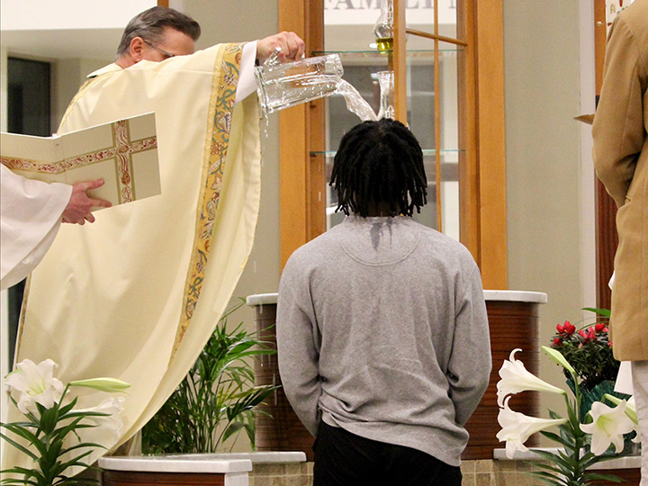 Fr. Kevin Mannara baptizes a student with water at the Hermance Family Chapel of St. Basil the Great.