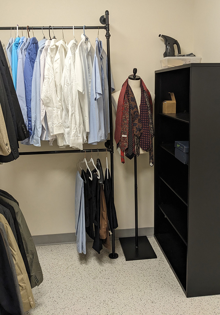 Dress clothes hanging on a rack next to a mannequin draped with ties.