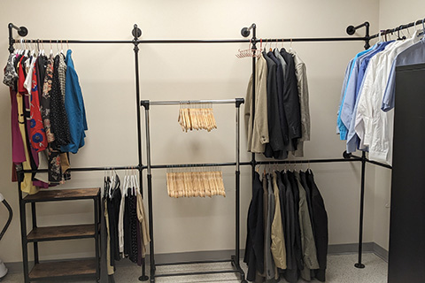 A closet with dress clothes on hangers.