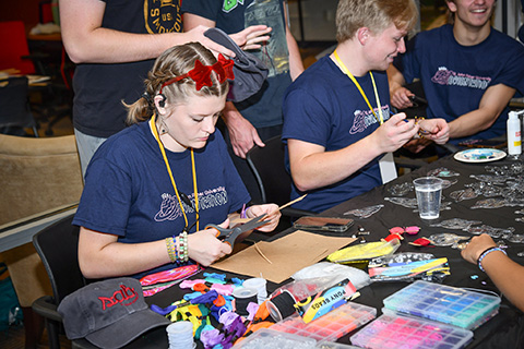 Students smile together while working on a craft project during Welcome Weekend.